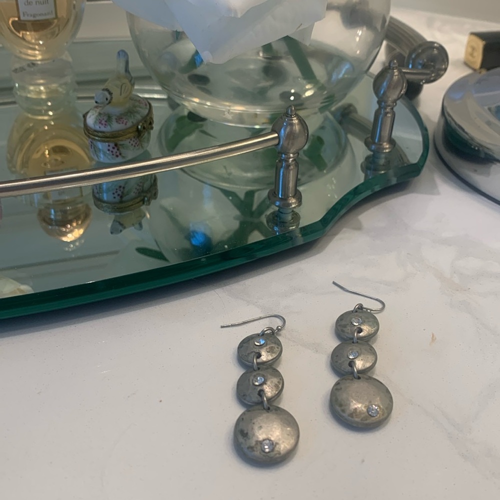 Pair of brushed silver earrings with crystals in the centers.